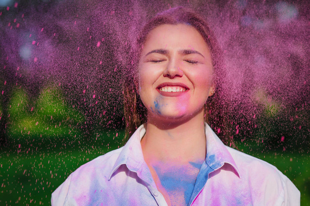 fröhliche kaukasische Frau posiert mit geschlossenen Augen mit explodierenden rosa Farbholi  - Foto, Bild