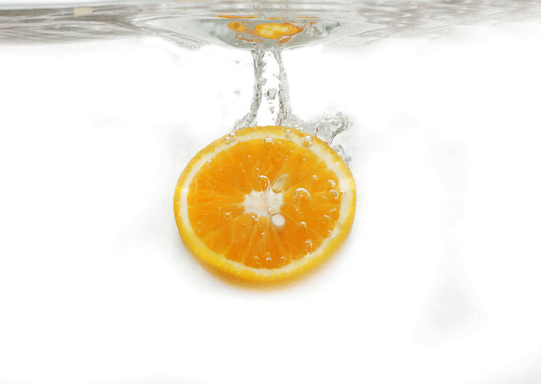 Plasterek świeżych pomarańczy wpada do wody - Zdjęcie, obraz