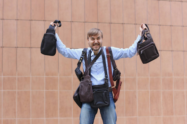 бородатий чоловік задоволений покупкою багатьох шкіряних пакетів, сумки на плечах і в руках, вирішені питання вибору
     - Фото, зображення