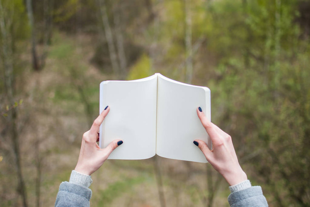 Chica sosteniendo un cuaderno. Manos pálidas y papel en blanco de cuaderno. Concepto (idea) de pensar, soñar, motivar, planear, estudiar. Contexto
 - Foto, Imagen