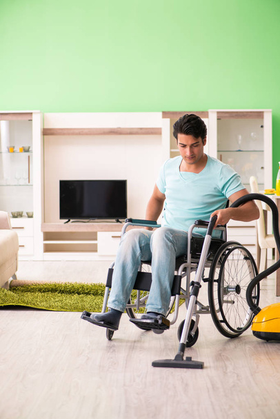 Gehandicapte man op rolstoel stofzuigen huis - Foto, afbeelding