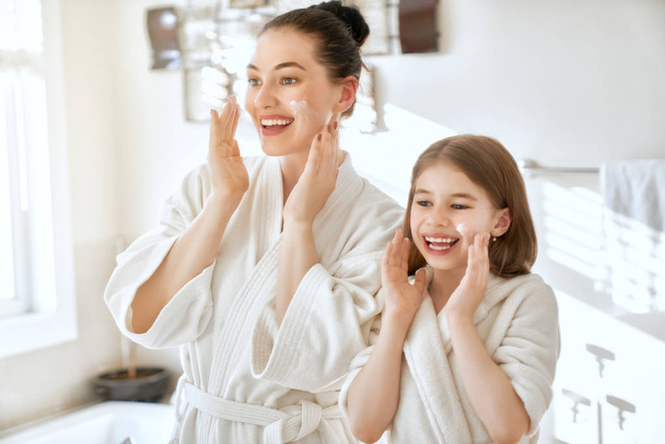 Happy family! Mother and daughter child girl are caring for skin in the bathroom. - Zdjęcie, obraz
