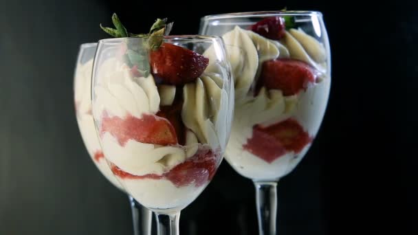 closeup three glasses with delicious white mousse creamy dessert with sliced strawberries served on black mirror background - Footage, Video