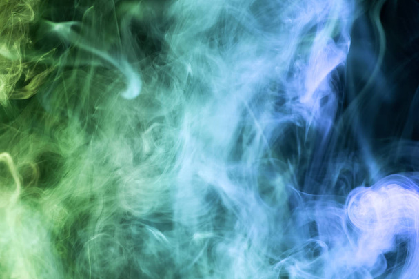 Kolorowe zielony i niebieski dym na czarno na białym tle. Tło z dymu vap - Zdjęcie, obraz