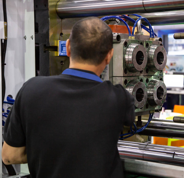 Arbeiter beim Aufbau einer industriellen Kunststoff-Spritzgießpresse für die Fertigung - Foto, Bild