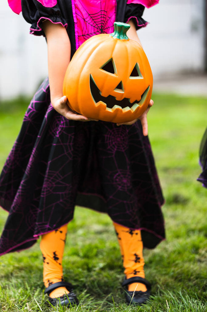 Menina detém uma laranja jack o lanterna Halloween decoração
 - Foto, Imagem