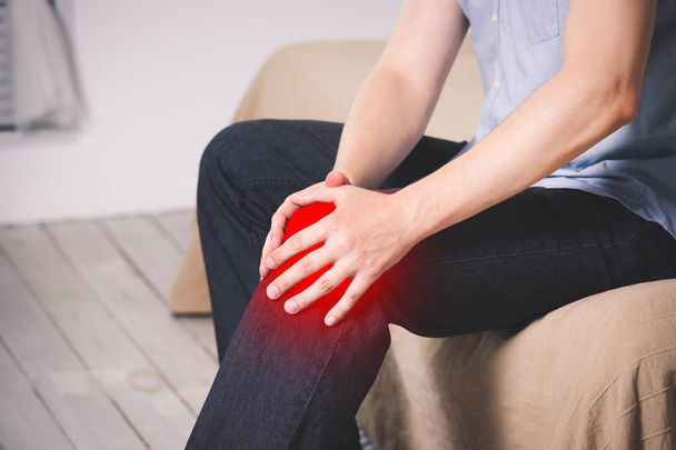 Man with pain in knee suffering at home, painful area highlighted in red - Fotó, kép