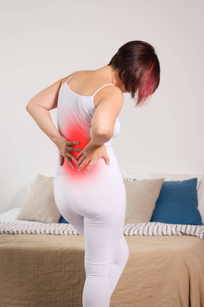 Back pain, kidney inflammation, woman suffering from backache at home, painful area highlighted in red - Fotoğraf, Görsel