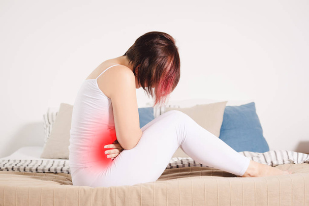 Dor de estômago, mulher com dor abdominal que sofre em casa, área dolorosa destacada em vermelho
 - Foto, Imagem