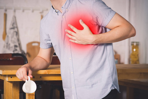 Heart attack, man with chest pain suffering at home, painful area highlighted in red - 写真・画像