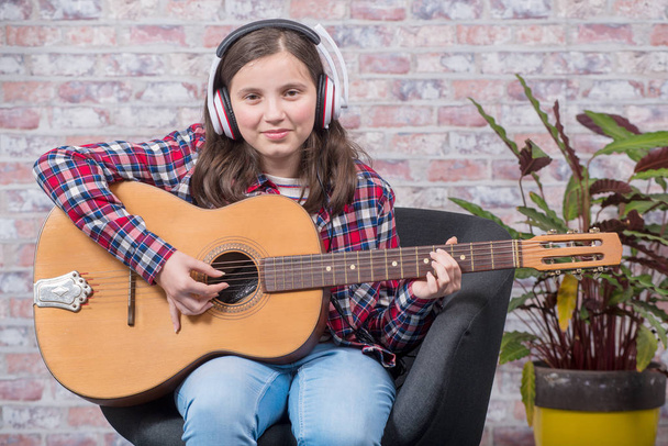 улыбающаяся девочка-подросток, играющая на акустической гитаре
 - Фото, изображение