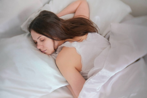 Jeune femme brune dormant dans le lit
. - Photo, image