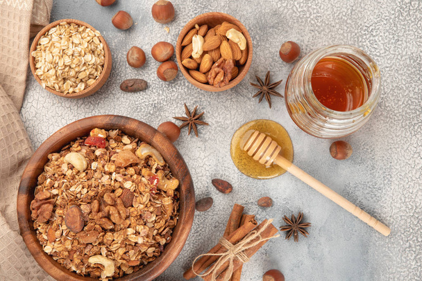 Granola casera en cuenco de madera con ingredientes - avena, nueces, miel y canela de especias y anís
. - Foto, imagen