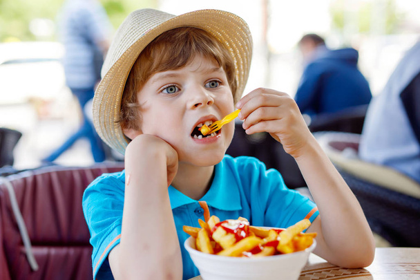 Милый здоровый дошкольный мальчик ест картошку фри с кетчупом
 - Фото, изображение