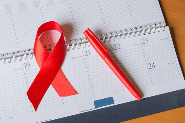 Red ribbon on the calendar to raise awareness against AIDS copy space - Photo, Image