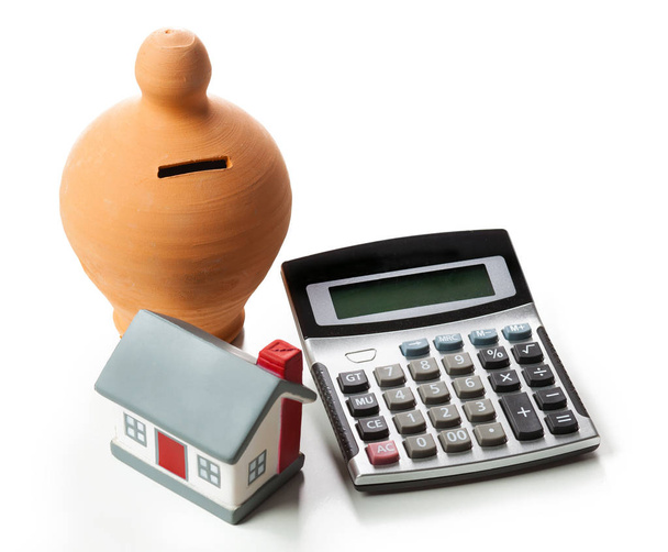 A koncepció a pénzügyi megtakarítások, hogy vesz egy házat. Persely és számológép elszigetelt fehér background. - Fotó, kép