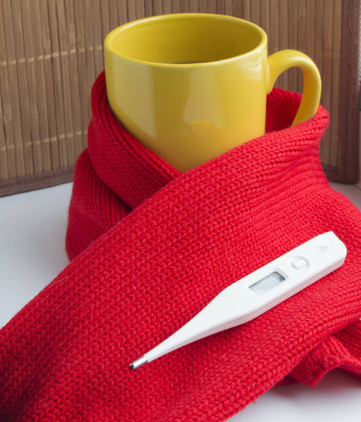 Concept van het behandelen van verkoudheid - hete thee met kaneel, thermometer, sjaal - Foto, afbeelding
