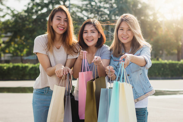 Група молоді азіатські жінки покупки в відкритий ринок з сумками в своїх руках. Молоді азіатські жінки показати, що вони отримали в кошику під теплих сонячних променів. Група відкритий торговий концепції. - Фото, зображення
