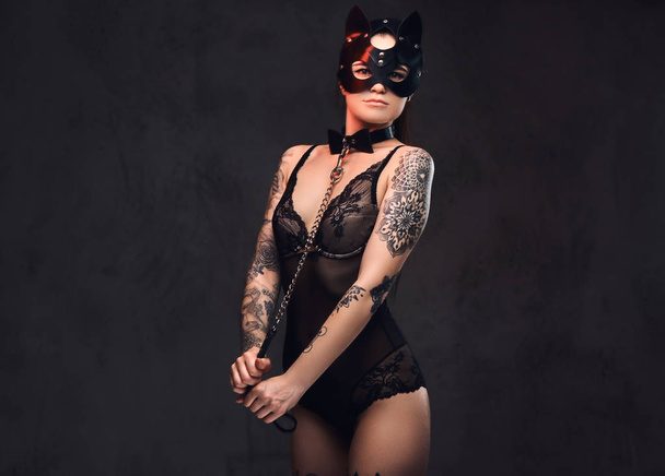 Sexy žena na sobě černé spodní prádlo v Bdsm maska kůže a příslušenství pózuje na tmavém pozadí.  - Fotografie, Obrázek