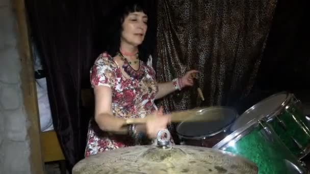 Volwassen vrouw plezier heeft, leert om te spelen op een oude vintage trommel instellen in een garage of kelder.  - Video