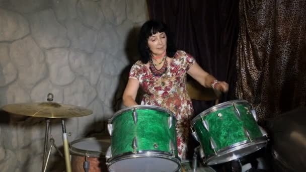Volwassen vrouw plezier heeft, leert om te spelen op een oude vintage trommel instellen in een garage of kelder.  - Video