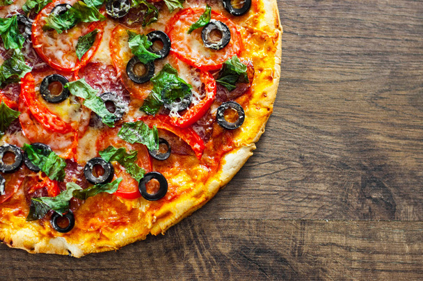 Pizza with Mozzarella cheese, salami, pepper, pepperoni, Tomatoes, olives, Spices and Fresh Basil. Italian pizza on wooden background. with copy space. top view - Fotó, kép