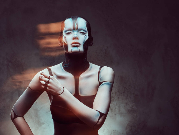 Retrato de uma mulher cibernética sensual com maquiagem criativa posando em um fundo texturizado escuro. Tecnologia e conceito futuro
. - Foto, Imagem