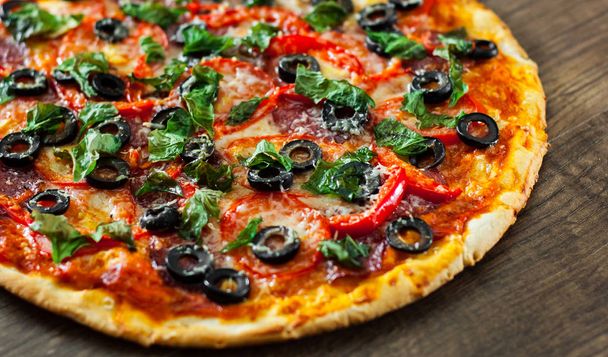Pizza with Mozzarella cheese, salami, pepper, pepperoni, Tomatoes, olives, Spices and Fresh Basil. Italian pizza on wooden background - Fotoğraf, Görsel