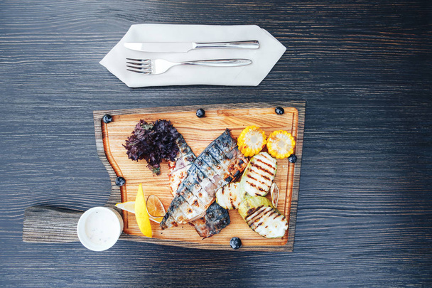 野菜と木製のまな板に魚のグリル。木製の背景。トップ ビュー - 写真・画像