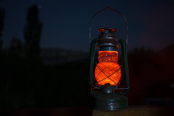 Horreur concept Halloween. Brûler une vieille lampe à huile dans la forêt la nuit. Paysage nocturne d'une scène de cauchemar. Concentration sélective
. - Photo, image