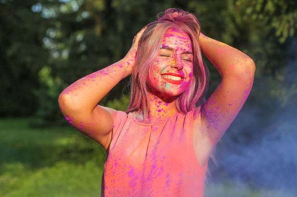 Retrato de close-up da menina caucasiana fabulosa coberta por tinta rosa e amarela Holi
 - Foto, Imagem