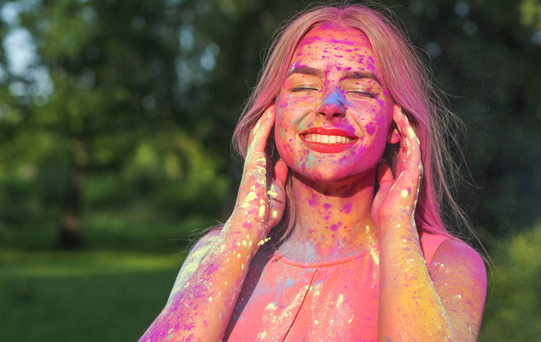 Cheerful blonde woman with long hair covered pink and purple dry paint Holi, space for text - Fotoğraf, Görsel