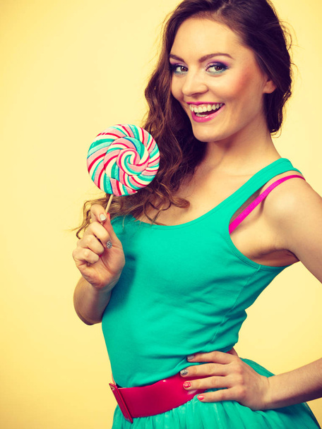 Woman attractive joyful girl holding colorful lollipop candy in hand having fun. Sweet food and happiness concept. Studio shot on bright toned image - Photo, image