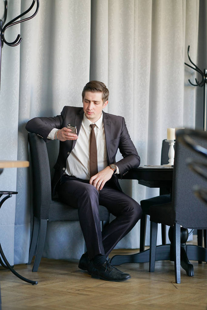 un giovane uomo in completo nero, camicia bianca e cravatta guardando il notiziario al telefono
 - Foto, immagini
