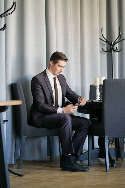 un jeune homme en costume d'affaires noir, chemise blanche et cravate regardant le fil d'actualité au téléphone
 - Photo, image