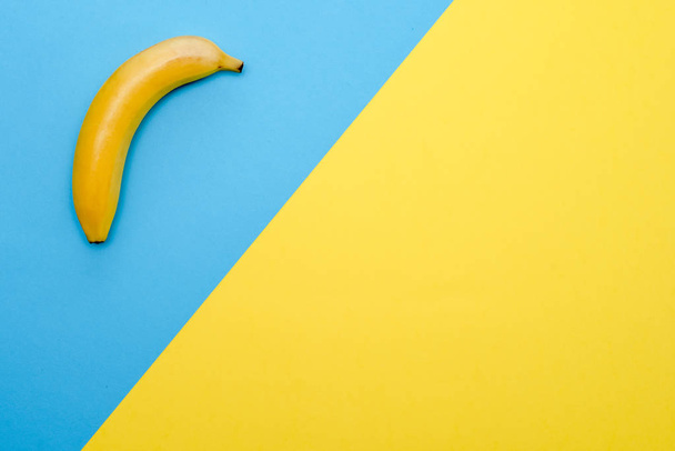 Diseño de diseño con plátano sobre fondo azul en la esquina superior izquierda y fondo amarillo en la derecha
 - Foto, Imagen