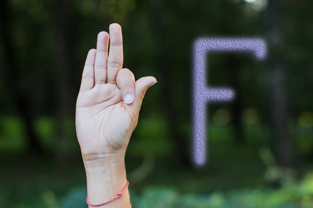 невербальный человек коммуникационная концепция дактиль алфавит от руки человека с буквой на несфокусированной размытой темно-естественной среды
  - Фото, изображение