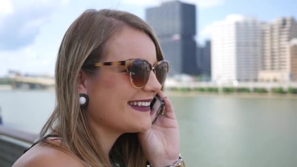 Beautiful brunette talks and laughs on her smartphone near downtown city area - Video, Çekim