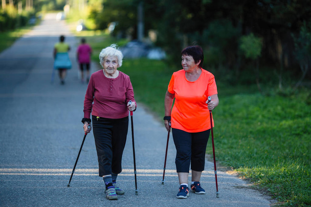 An elderly women is engaged in Nordic walking with her adult daughter. - Photo, Image