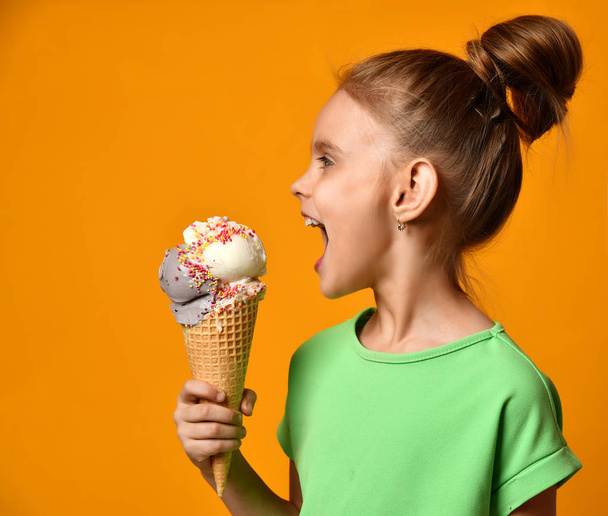 Pretty baby girl kid eating licking banana and strawberry ice cream in waffles cone - 写真・画像