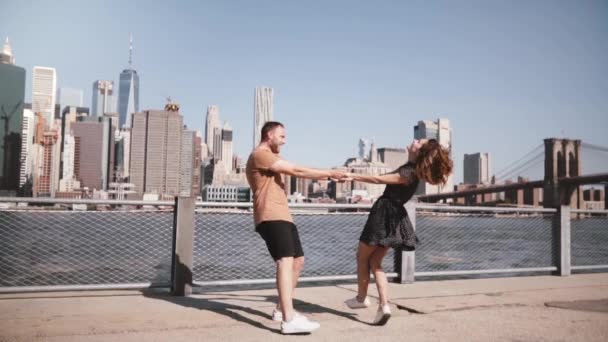 Wesoły Europejska para zrobić spin szczęśliwy taniec w pobliżu słynnego panoramę Nowego Jorku Manhattan, trzymaj ręce zwolnionym tempie. - Materiał filmowy, wideo