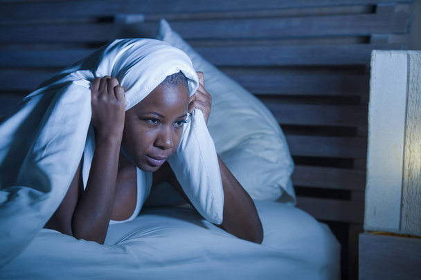 lifestyle night portrait of young sad and stressed black afro American woman lying on bed upset trying to sleep suffering insomnia and depression feeling anxiety crisis and sleeping disorder problem - 写真・画像