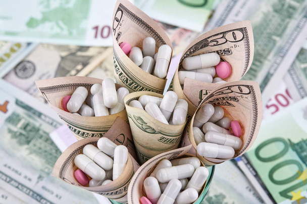 Pílulas brancas e cor-de-rosa em notas de dólares americanos em notas de euro
. - Foto, Imagem