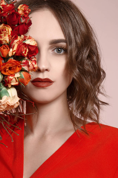 schönes Mädchen mit Blumen. fabelhaftes Frühlingsporträt einer jungen Frau mit Make-up und rotem Kleid. Sommersymbol - Foto, Bild