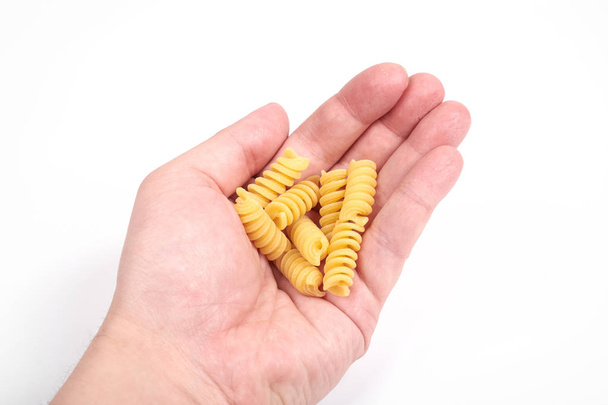 fusilli pasta noodles in a hand, isolated on a white background - Photo, Image