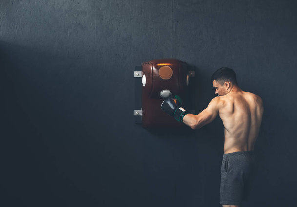 Sportsman is hitting punching bag indoor - Photo, Image