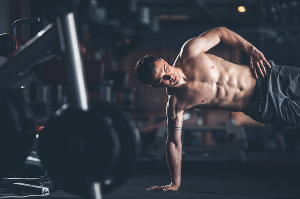 Determined man is balancing on one arm in gym - Photo, Image