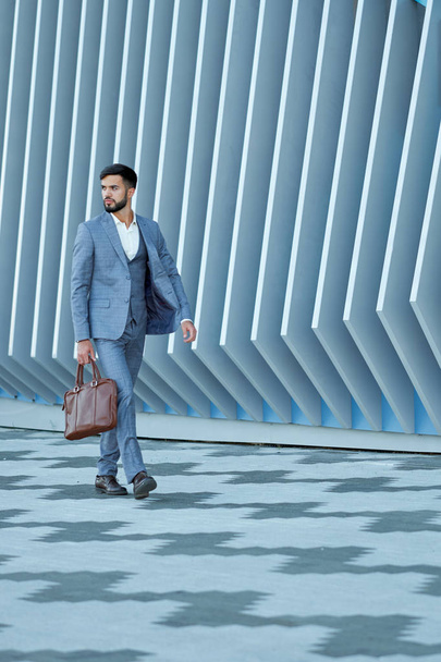 Businessman in formal wear with leather bag walking in city - Photo, image