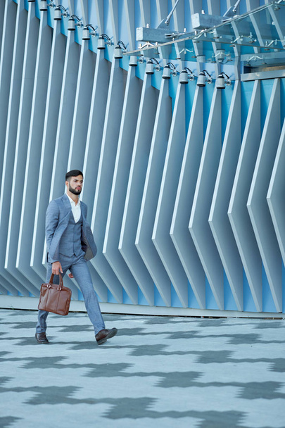 Businessman in formal wear with leather bag walking in city - Zdjęcie, obraz