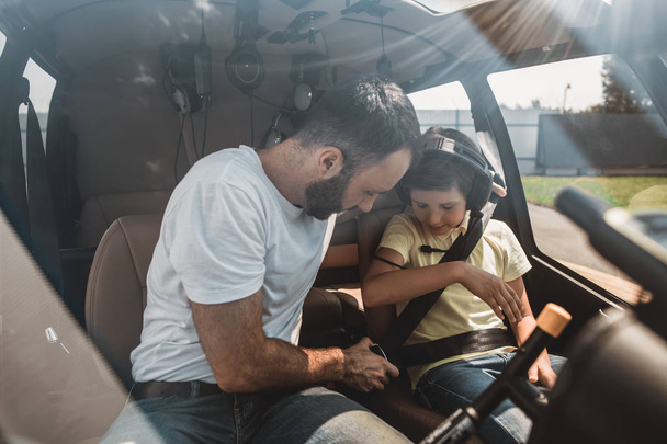 Calm man instructing satisfied boy in helicopter - Фото, зображення